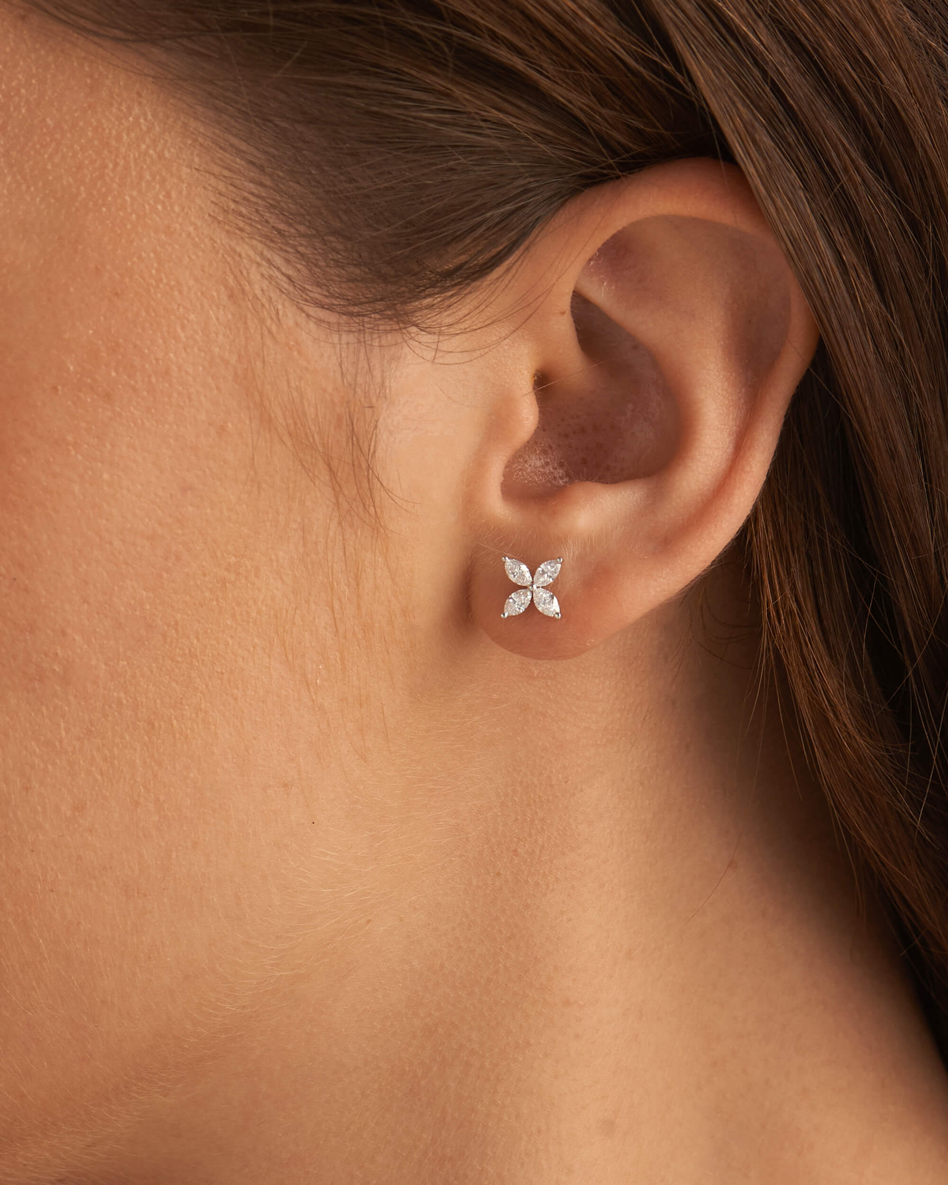 Close-up of an ear wearing a diamond flower earring.