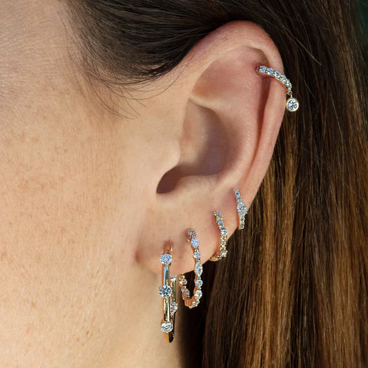 Close-up of an ear wearing multiple diamond hoop earrings.